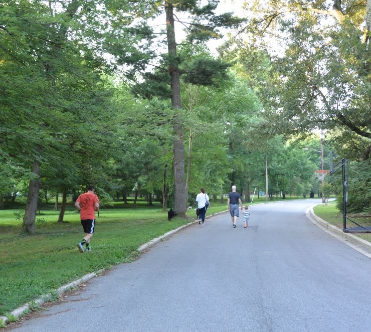 Walkers and a jogger on a street without a sidewalk