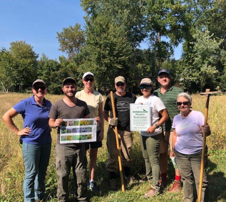 A group of University Park residents and volunteers stand in the pollinator meadow 