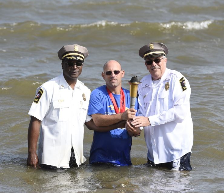 Chief Baker and LT Enig pose with Special Olympics participant in the water