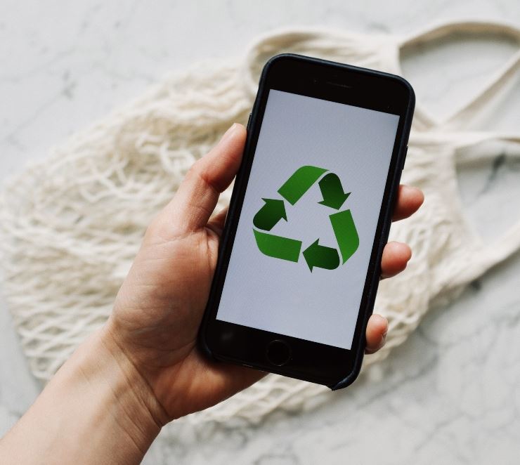 person holding a cell phone showing the recycling icon