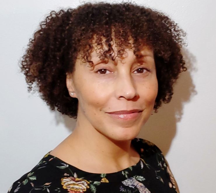 TC Hegeman smiles at the camera while wearing a black floral printed shirt 